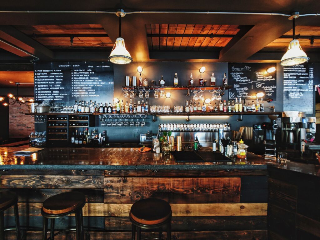 A photo of a bar counter with stools in front of it where people would tip.