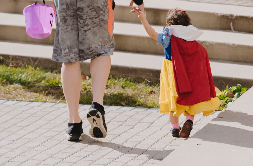 A parent taking their child trick or treating on Halloween.