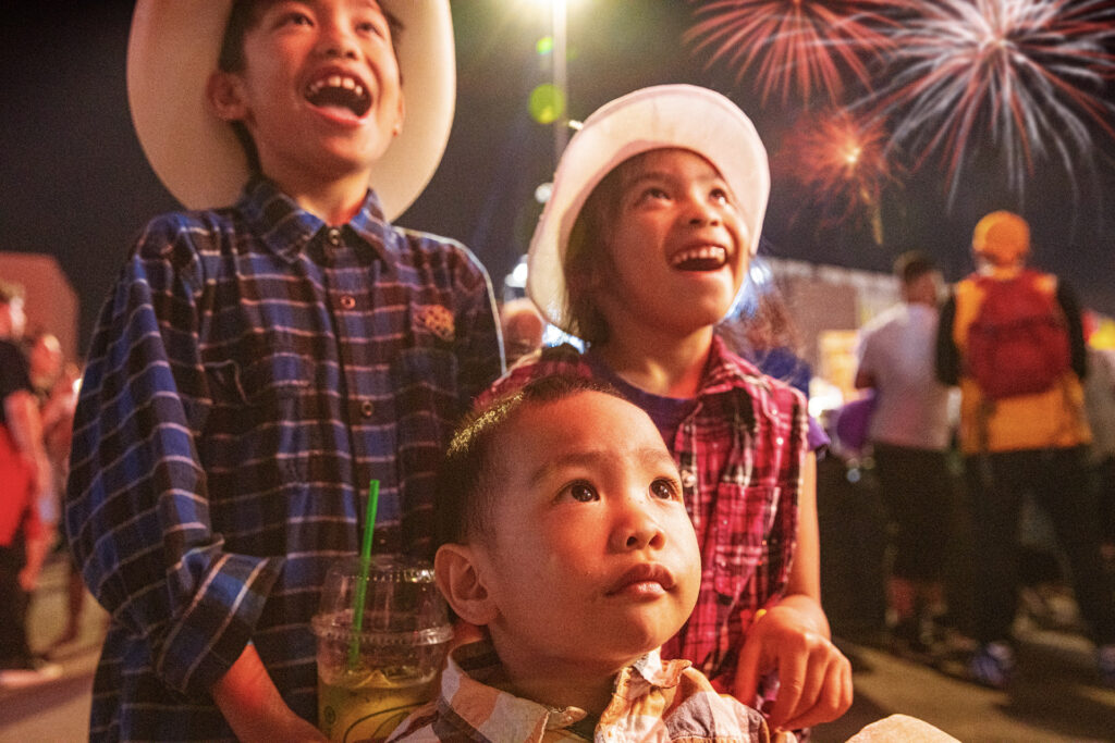 Children in awe at the Calgary Stampede with fireworks in the background.