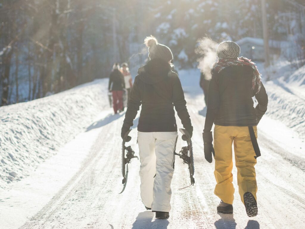 People dressed warm for a Canadian winter while snowshoeing outside.