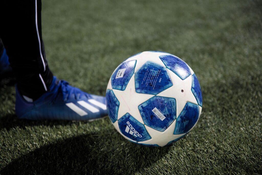 Person standing next to a blue football with white stars on it.